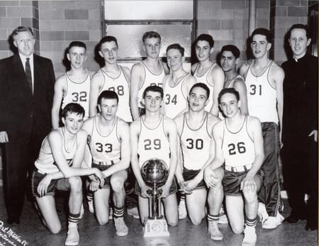 Black and white photo of a vintage basketball team posing with a trophy.